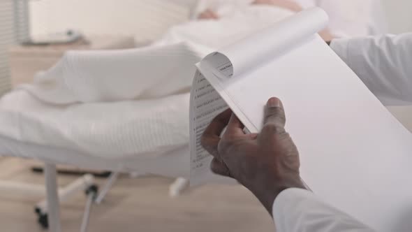 Doctor Filling Medical Documents of Patient at Hospital Ward