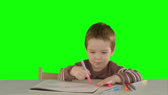 A Son Drawing At The Table At Home On a Green