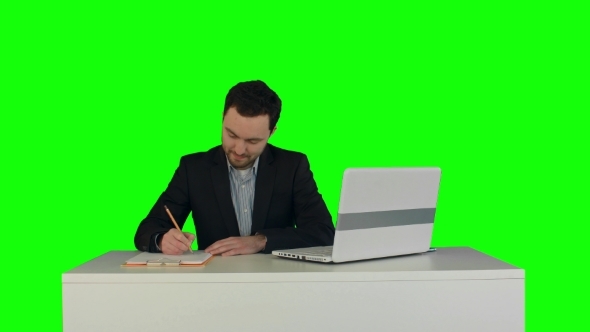 Human Hand Writing On a Paper With Laptop On a