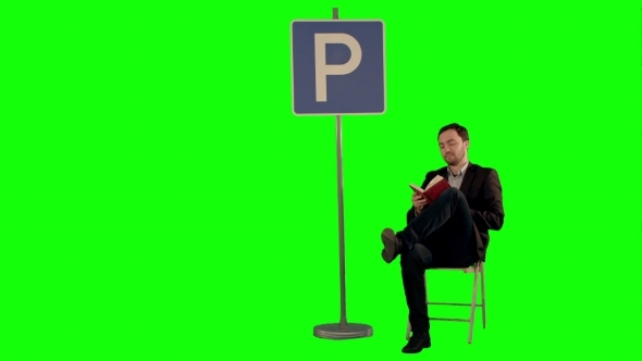 Businessman Reading a Book Near Parking Sign On a