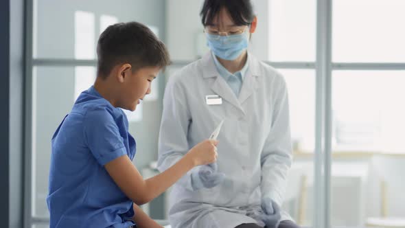 Asian Pediatrician Taking Temperature of Sick Kid