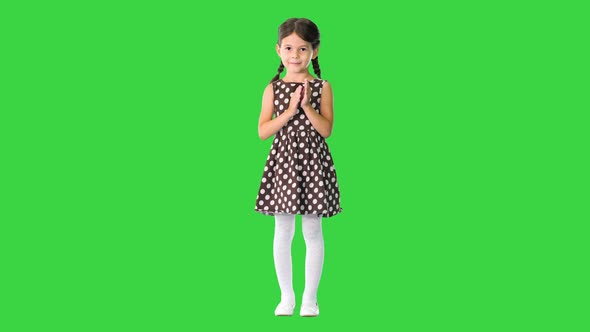 Little Girl in Polka Dot Dress Clapping Her Hands Looking at Camera on a Green Screen Chroma Key