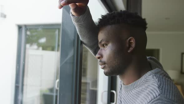 Video of sad african american man looking outside window