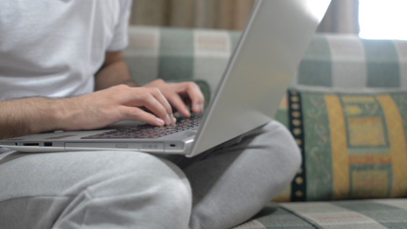 Typing on Laptop,By Casual Man Sitting on Sofa