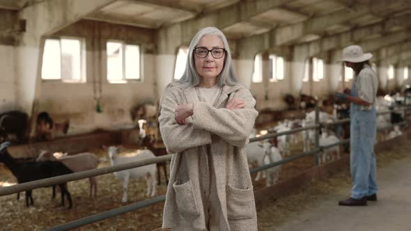 Aged Woman Standing with Crossed Arms at Own Goat Farm