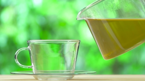 Steaming Cup Of Tea And Teapot On Blur Background