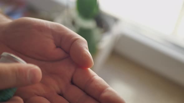 Two White Pills Fall on Palm From Bottle