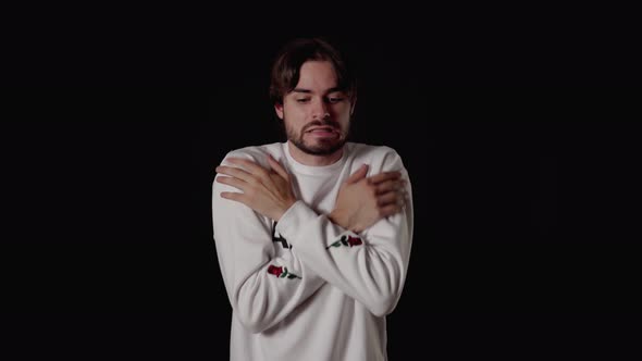 Trendy Young Man freezing gesture, shaking and warming himself, wide, black background