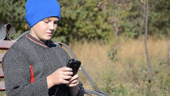 A Boy Playing With a Smartphone