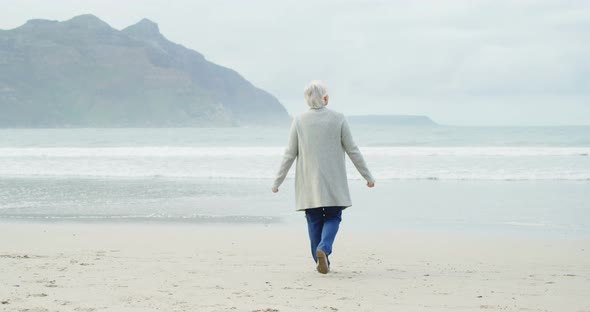 Rear view of senior woman walking on beach