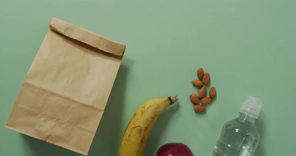 Animation of paper lunch bag an fruits on blue background