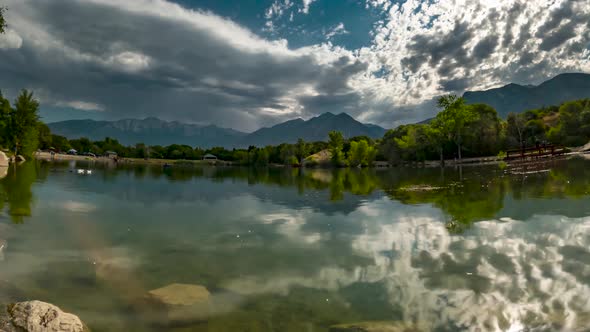 Cloudscape above the pond and mountains with the dynamic clouds reflecting off the surface of the wa