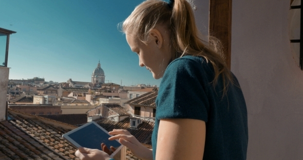 Woman Using Pad On The Balcony With City View