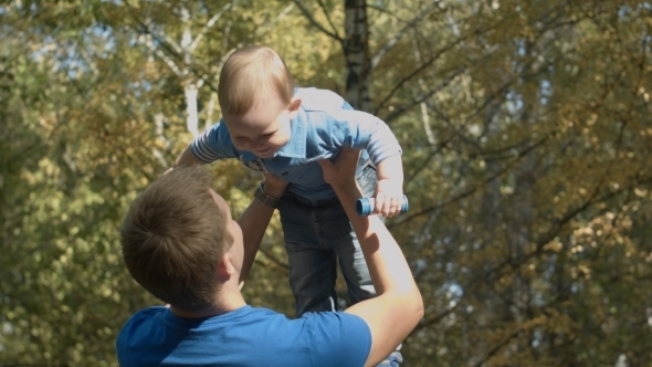 Dad Tosses Son Into The Air In An Autumn Park