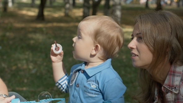 Happy Mother And Son In The Park Blowing Soap