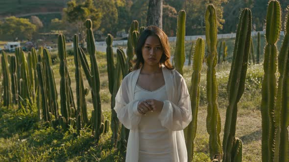 Young Asian Woman in a Cactus Field at Sunset Looking at Camera