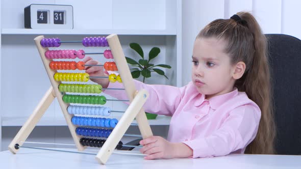 Little Girl in Shirt Sitting at the Table and Said To the Multicolored Aba