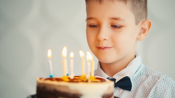 Little Boy Blowing Out Candles On Birthday Cake