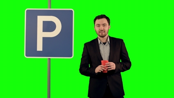 Man With Cup Of Tea Near Parking Sign On a Green
