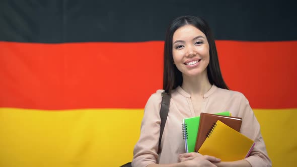 Happy Female Student Holding Copybooks Against German Flag Background, Education