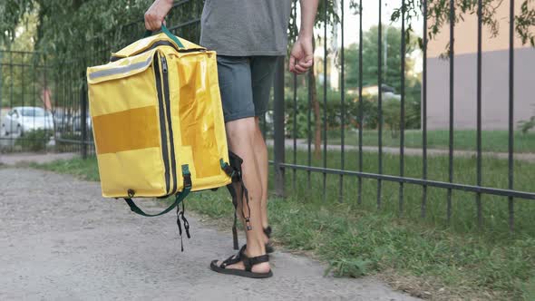 A courier with a yellow backpack delivers an online order. Stay home, self-isolation.