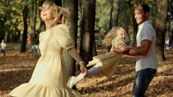 Little Girl And Her Parents Playing In The Autumn