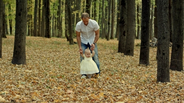 Father And His Baby Make First Step In Autumn Park