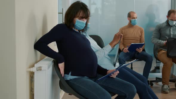 Pregnant Woman with Face Mask Sitting in Waiting Queue