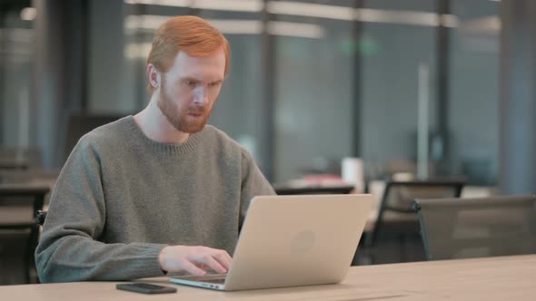 Young Man Celebrating Success While Using Laptop in Office