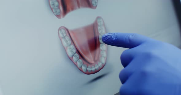 A Doctor in Hygienic Gloves Uses a Tablet Moving His Finger Across the Screen