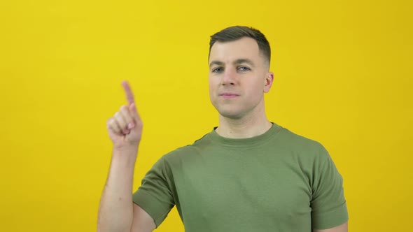 A Man in a Green Tshirt Raises His Index Finger Up to Face Level