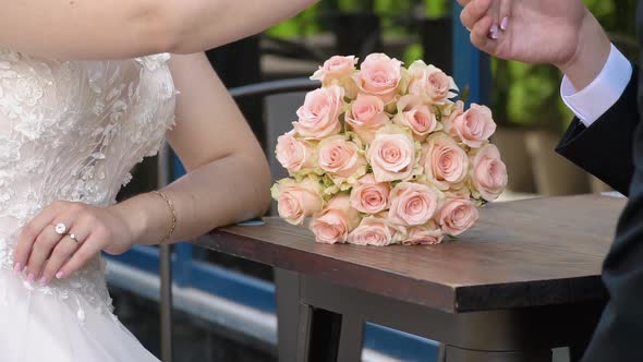 The Bride and Groom on Their Wedding Day Sitting at a Table with the Bridal Bouquet