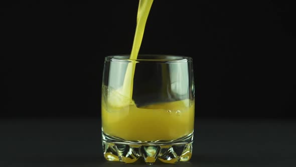 Juice Pouring Into Glass Isolated on Black Background Slow Motion