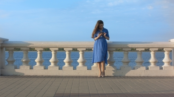 Beautiful Girl In Blue Dress Using Digital Tablet.