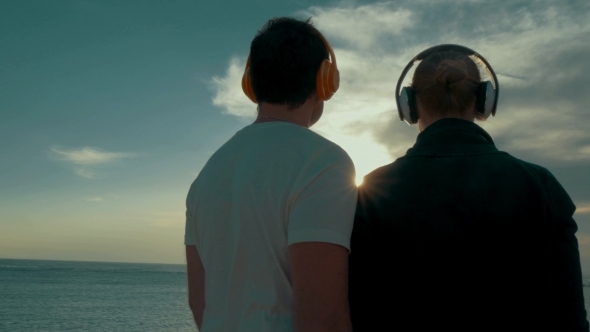 Young Couple In Headphones Enjoying Sea And Sky
