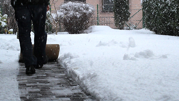 A Man Shovels Snow from a Walkway
