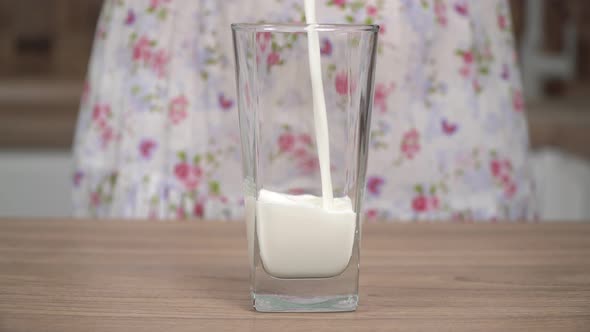 A Woman in the Kitchen Pours Milk Into a Glass