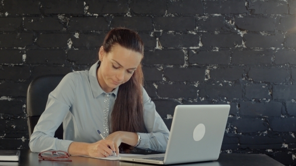 Businesswoman With Laptop Writes On a Document At