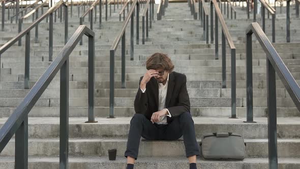 Sad businessman is sitting on the steps of the stairs.