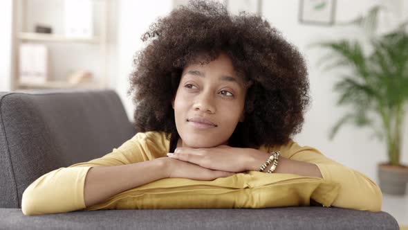 Thoughtful Young African American Woman Looking Away While Relaxing on Sofa