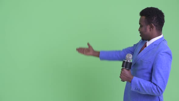 Happy Young African Businessman As Newscaster Presenting Something