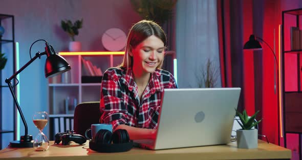 Young Blondie in Casual Clothes Sitting in Front of Computer and Chatting with Friends at home