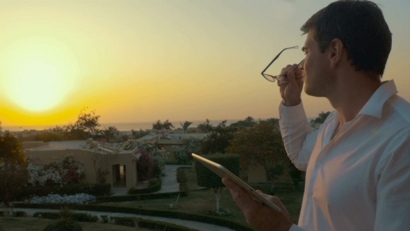 Man Putting Glasses On To Write In Tablet