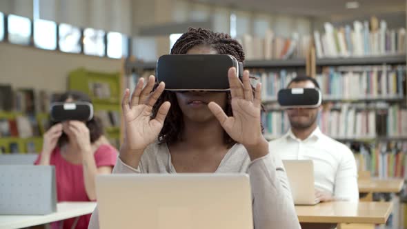 Front View of Excited Woman Sitting in Library and Experiencing VR