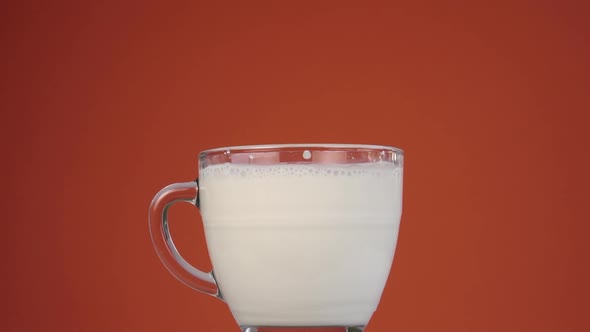 Popping bubbles of fresh milk froth in a full clear glass cup