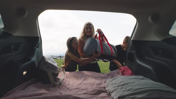 Mother and Kids Packing Bags Into Trunk