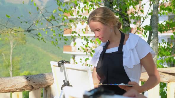 Woman Painter Is Working on Picture Outdoors