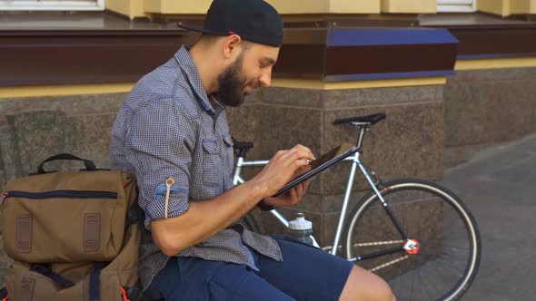 Cyclist Uses Tablet on the Street