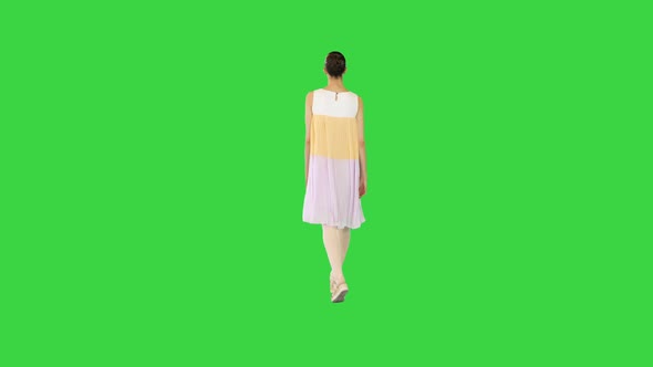 Young Beautiful Girl in Whiteyellow Dress Walks Slowly on a Green Screen Chroma Key