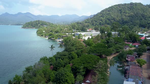 Aerial of a tropical beach front by the beach on an island with mountains in the background